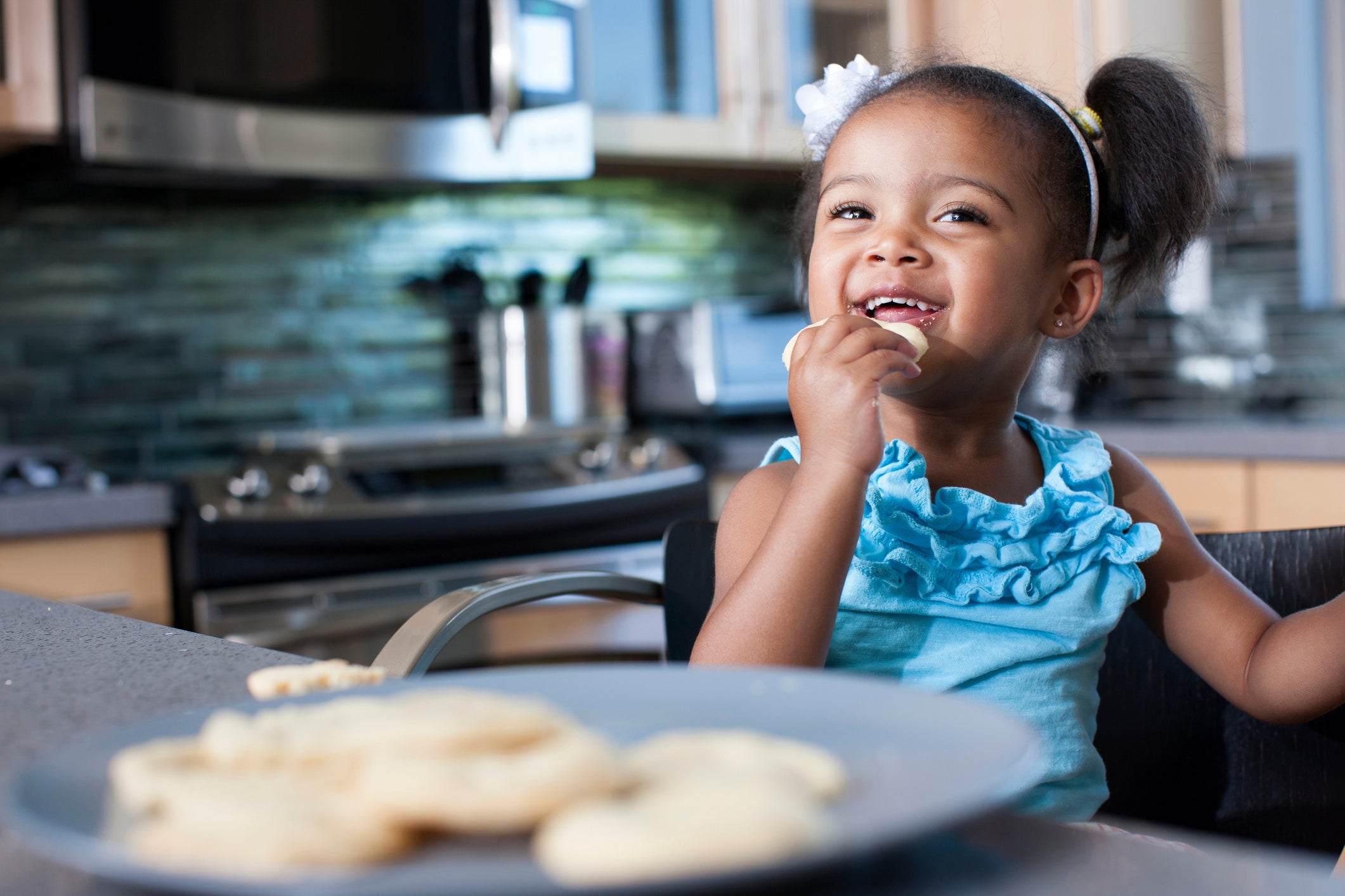 A smilling girl eating a cookie.