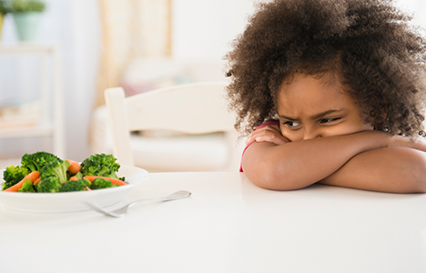 A child rejecting a plate of vegetables essential for iron deficiency.