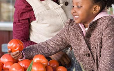 A girl helping her mom choosing fruits and vegetables.